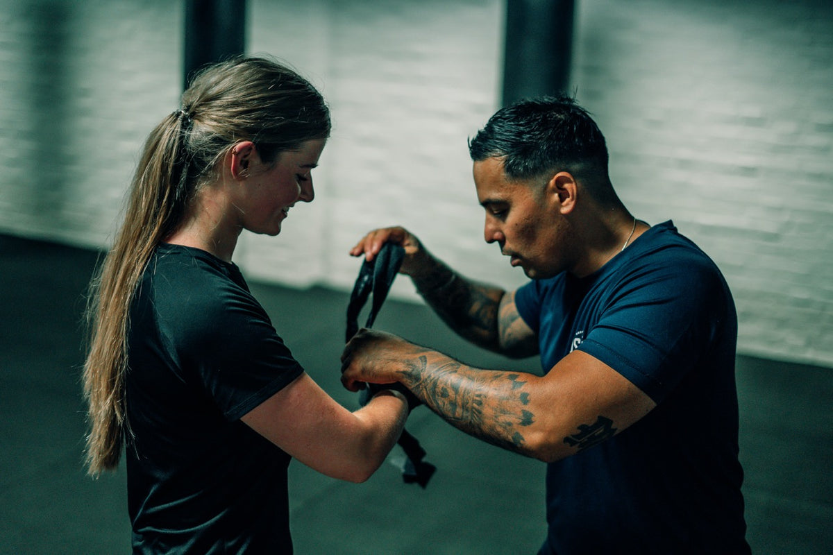 Trainer Menno Tubalawony legt bandages om de handen van een vrouw tijdens personal training bij Usaha Boksen in Tilburg